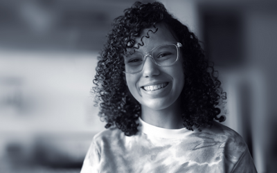 teenage girl with glasses and curly hair smiling at the camera
